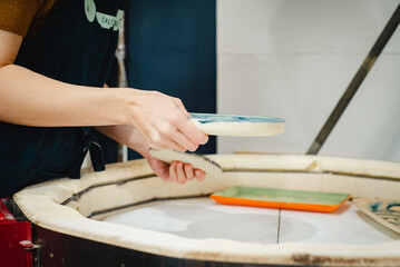 Potter unloading ceramic kiln in studio. Woman potter hands.