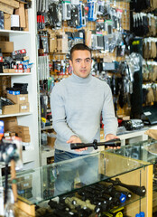 Salesman standing at counter in arms shop and presenting rifle telescope.