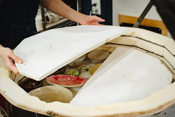 Potter unloading ceramic kiln in studio. Hands and pottery. Large kiln trays.