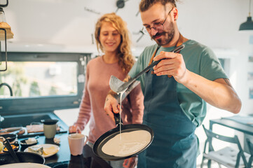 Young couple making breakfast together in the kitchen at home