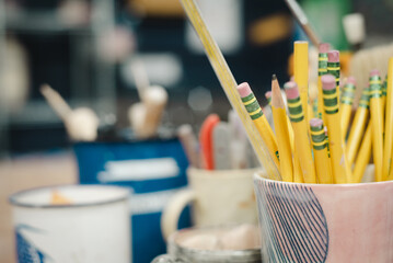 Potter studio brushes and tools closeup, pencils, paintbrushes in ceramic workshop