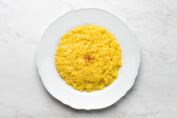 Risotto Milanese  in a white aristocratic dish on a white marble background. A classic Lombard...