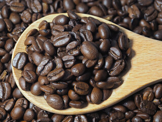 Roasted coffee beans in a wooden spoon. Selective sharpness.