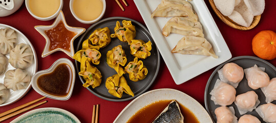 Chinese new year festival table over red background. Traditional lunar new year food. Flat lay, top view. Banner