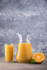 Fresh orange juice in decanter and glass on marble background.