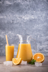Fresh orange juice in decanter and glass on marble background.