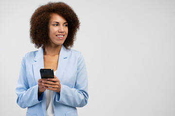 Beautiful smiling African American woman holding smartphone using mobile app shopping online isolated on background, copy space 