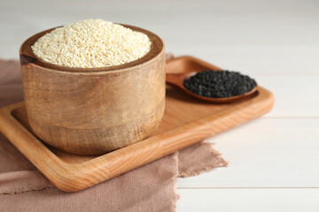 DIfferent sesame seeds on white wooden table, space for text