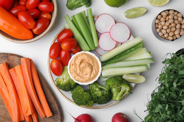 Plate with delicious hummus and fresh vegetables on white table, flat lay