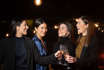 group of young women toasting with champagne glasses with elegant dresses