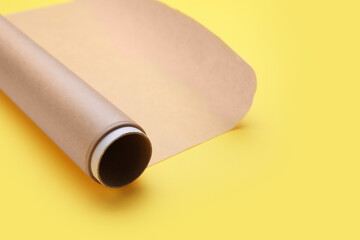 Roll of baking paper on yellow background, closeup