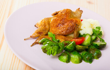 Baked spicy tobacco quail with vegetable garnish of steamed cauliflower, Brussels sprout, fresh tomato and parsley