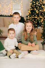 Three children near the Christmas tree. Siblings at Christmas at home	