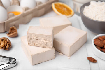 Blocks of compressed yeast and ingredients for dough on white table, closeup