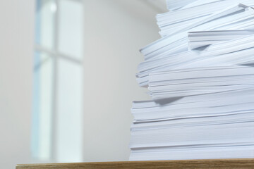 Stack of paper sheets on wooden table against blurred background, closeup. Space for text
