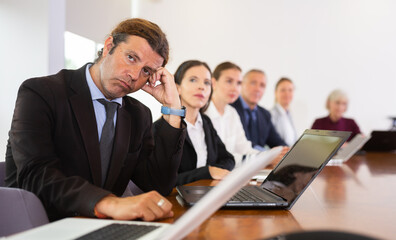 Depressed mid aged white businessman distracted from corporate meeting looking with eyes full of...