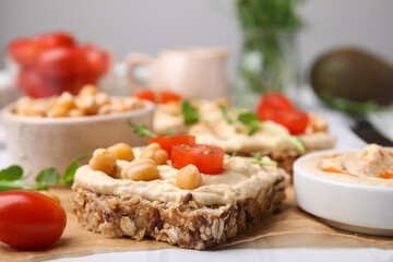 Delicious sandwiches with hummus and ingredients on wooden board, closeup