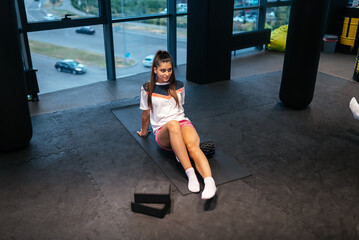 Young woman using a foam roller while doing stretching exercises