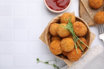 Bowl of delicious fried tofu balls with pea sprouts and sauce on white tiled table, flat lay. Space for text