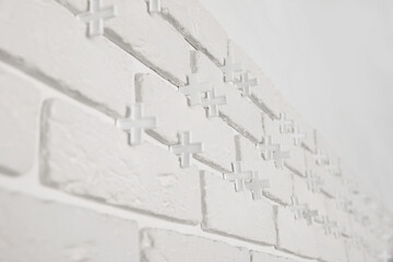 Decorative white bricks with tile leveling system on wall