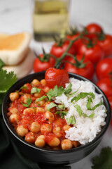 Delicious chickpea curry with rice in bowl on table, closeup