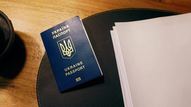 Table top view over a blue Ukrainian passport near blank paper