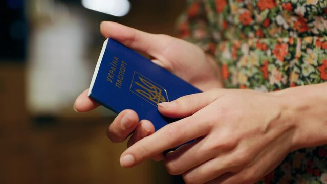 Scared shacking female refugee holding a Ukrainian passport in hands