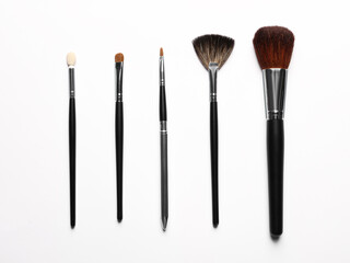 Different makeup brushes on white background, flat lay