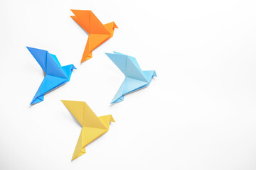 Beautiful colorful origami birds on white background, flat lay. Space for text