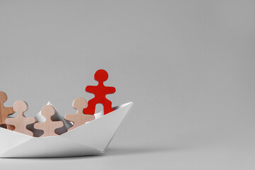 Red figure among wooden ones in paper boat on white background, space for text. Recruiter searching employee