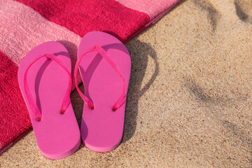 Fototapeta na wymiar Beach towel and slippers on sand, space for text