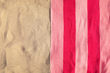 Fototapeta premium Soft pink beach towel on sand, top view. Space for text