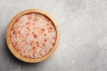 Bowl with natural sea salt on light grey table, top view. Space for text