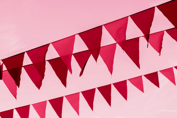 Garland of triangular flags, pennants against sky, toned background, magenta color