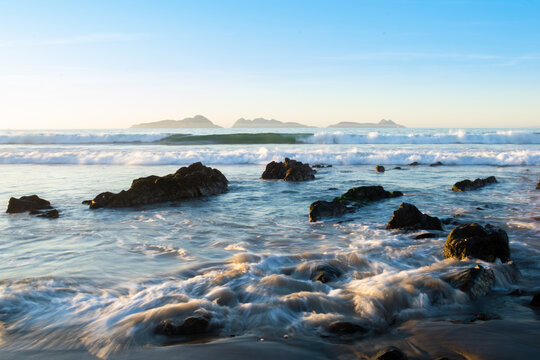 Rocks on beach with distant view of Cies islands, Nigran, Galicia, Spain