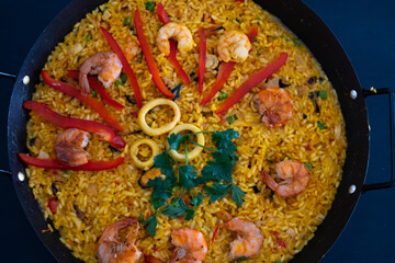 Classic dish of Spain, seafood paella in traditional pan on dark blue background top view