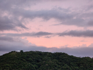 Pink  sunset over green hill with house