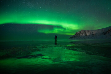 Man watching Northern Lights on a beach in Northern Norway