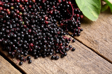Pile of tasty elderberries (Sambucus) on wooden table, space for text
