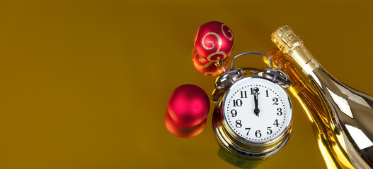 New Year celebration at midnight on gold background with partial champagne bottle and red ball ornaments plus clock