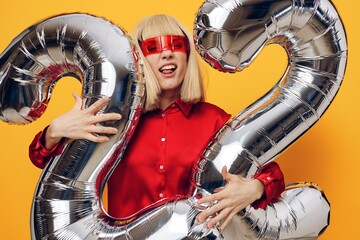 an emotional blonde woman stands on a yellow background in futuristic red glasses, in a red shirt...