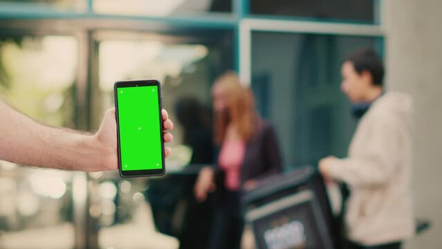 Person showing greenscreen display on smartphone outside, courier delivering meal order at client front door. Holding mobile phone with chroma key, using isolated mockup template with copyspace.