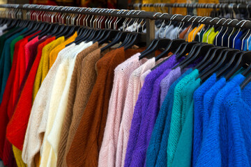 Close up view of stand with various sweaters and cardigans in clothing shop