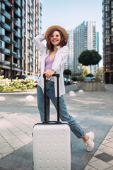 Stylish woman with suitcase looking at camera