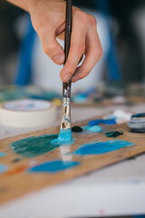 Artist mixes paints with a brush on a palette