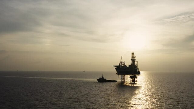 Jack up drilling rig and production platform in the middle of the ocean at sunrise time
