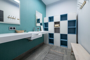 Locker room of a gym with designer white porcelain sink, blue locker and white doors and beech wood seat