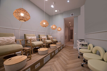 Beauty salon with a line of pedicure stands with velvet and wood hammocks and brass faucets