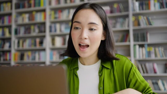 Young female teacher conducts online lesson from library