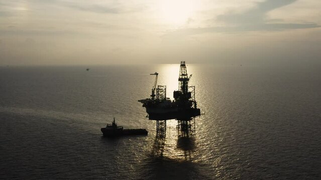 Jack up drilling rig and production platform in the middle of the ocean at sunrise time
